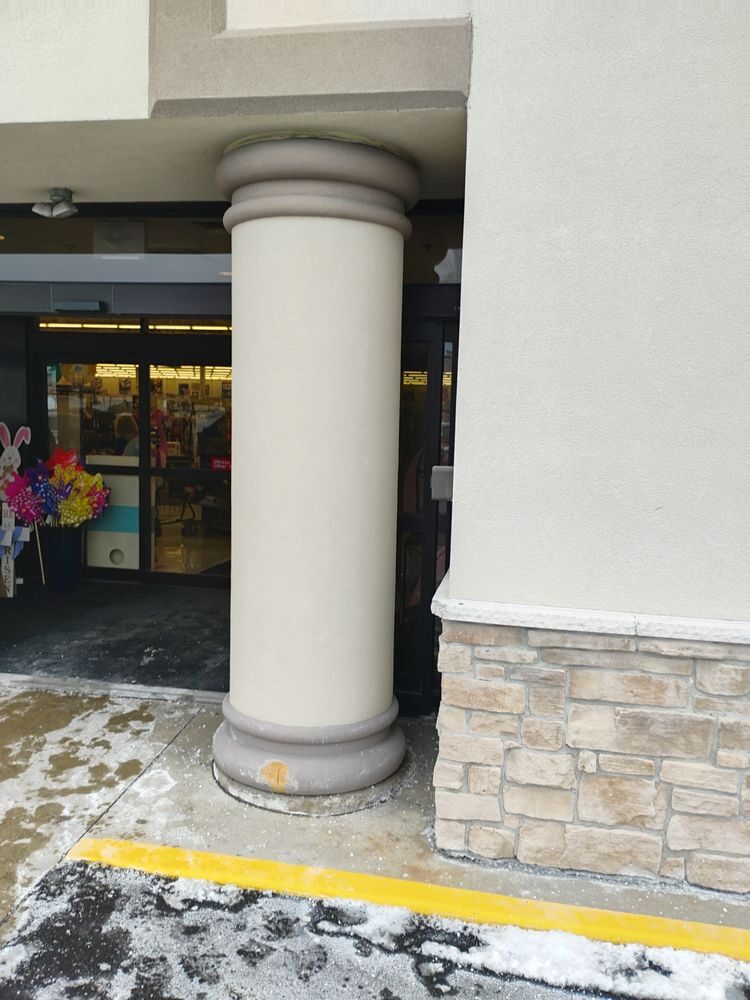 A refinished white column with a stone base at a storefront entrance.